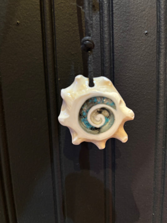 Decorative seashell pendant necklace with a spiral design on a black background