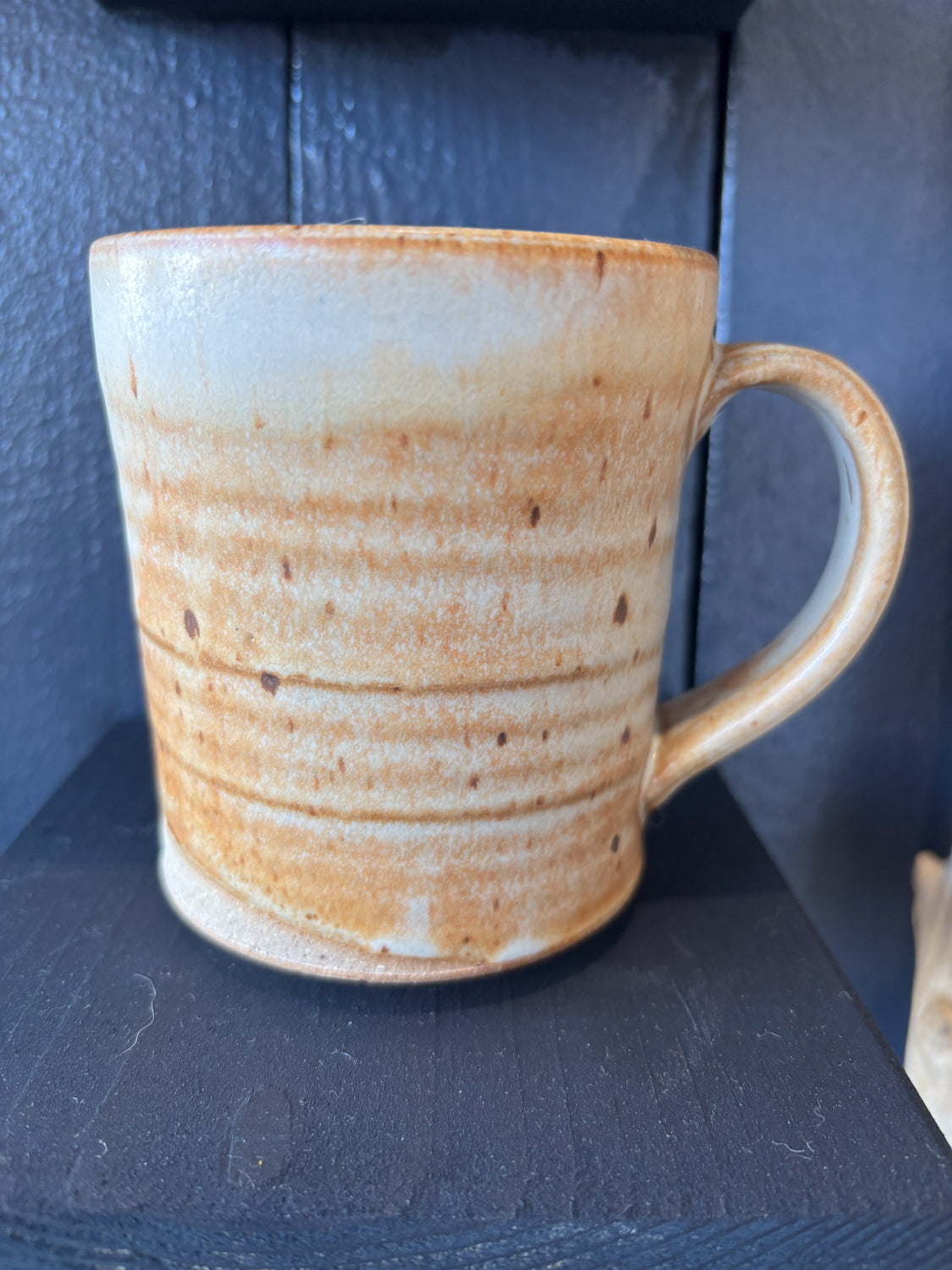 Ceramic mug with brown and white speckled pattern on a dark surface