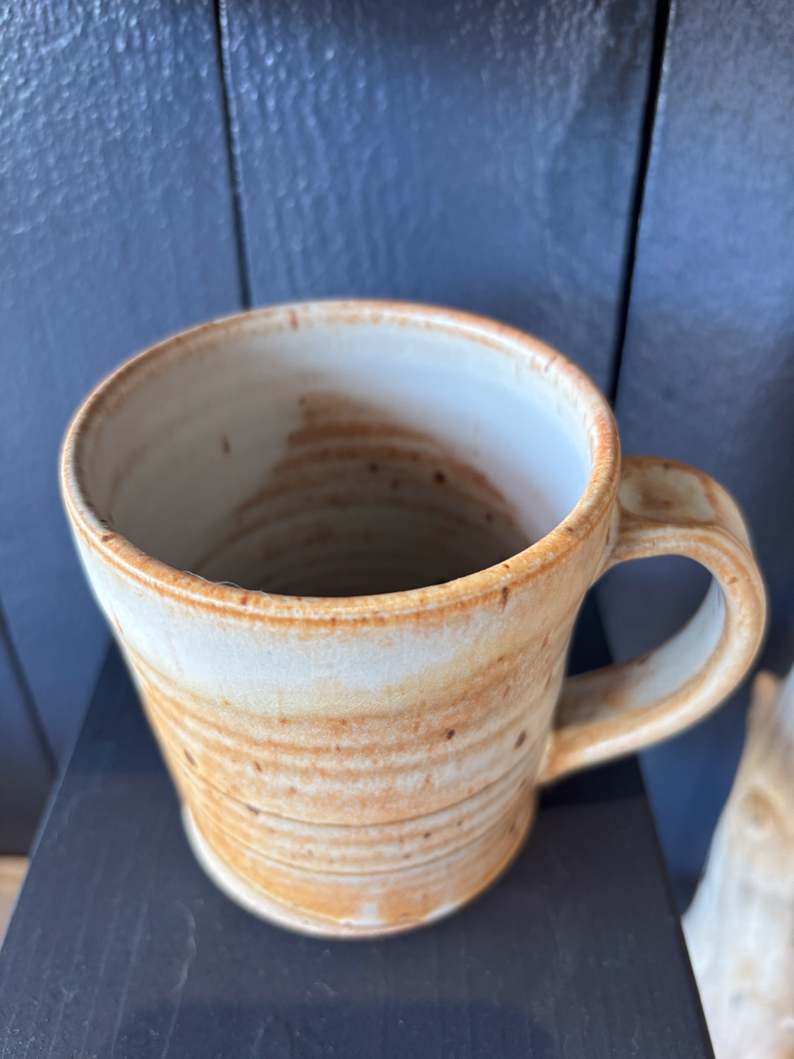 Ceramic mug with natural brown markings and handle on a dark surface