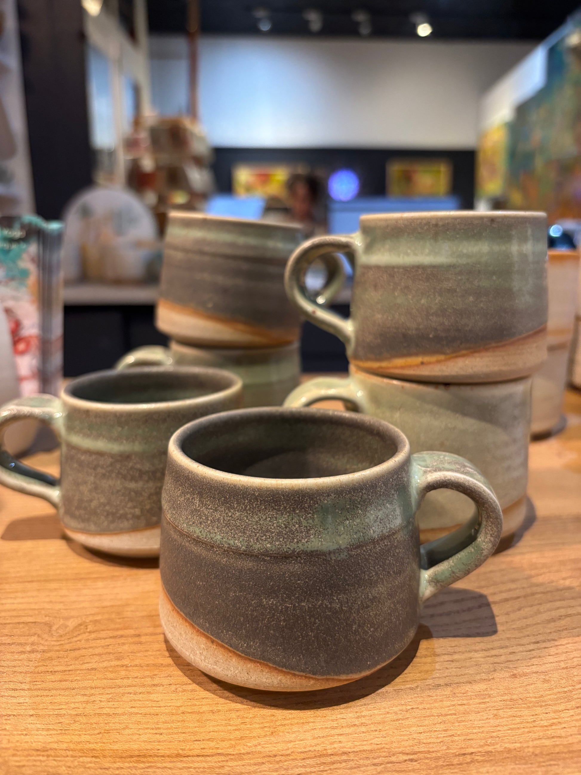 Set of ceramic mugs on a wooden surface with a blurred background