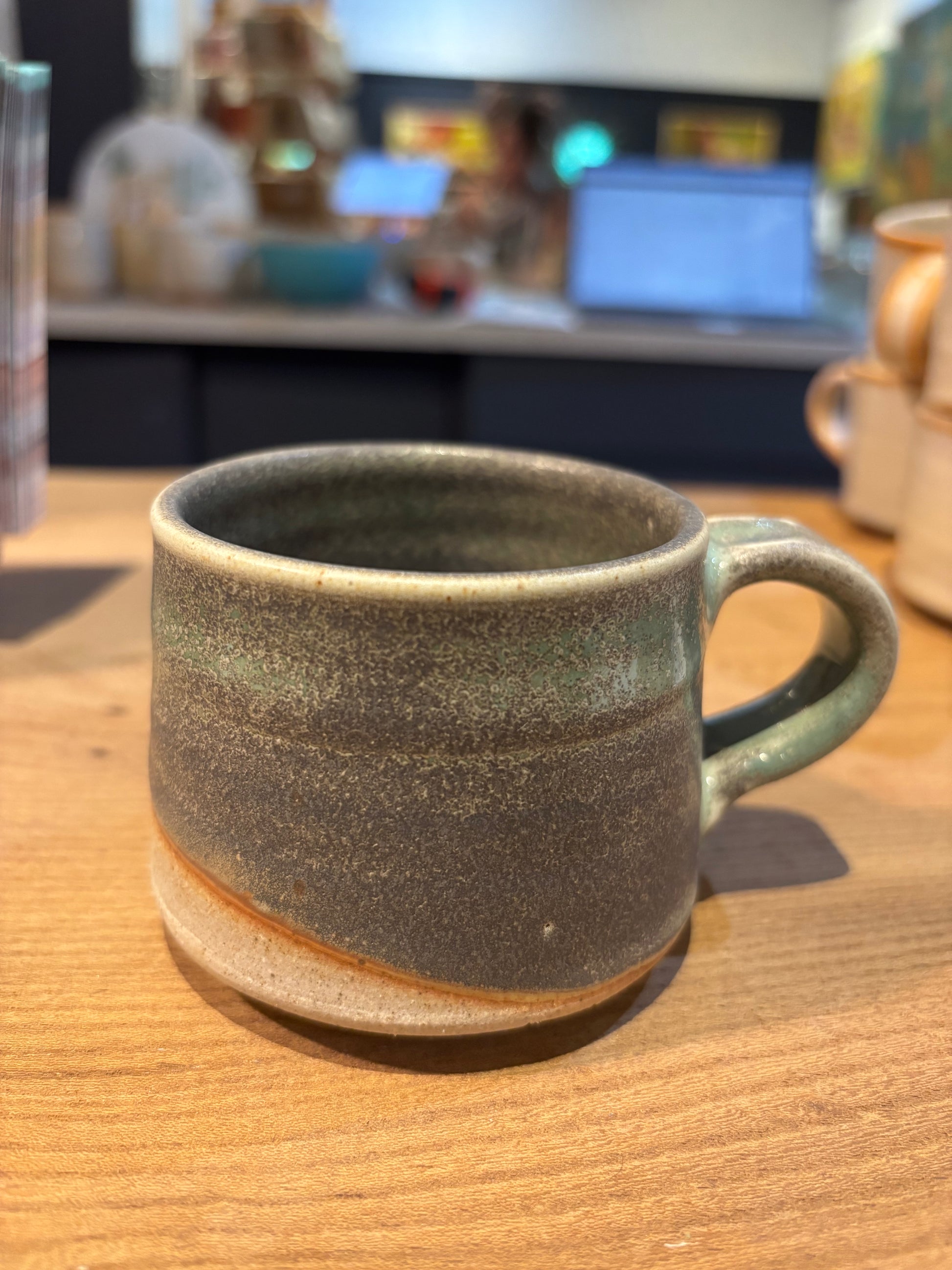 Green ceramic mug on a wooden table with a blurred background