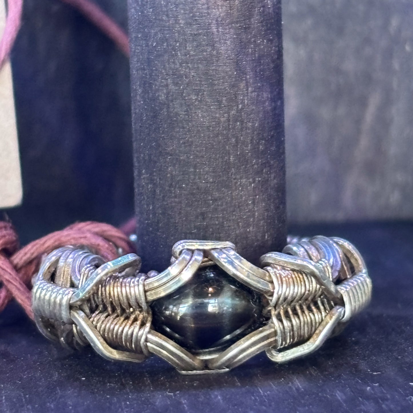 Silver bracelet with a central black bead on a dark background