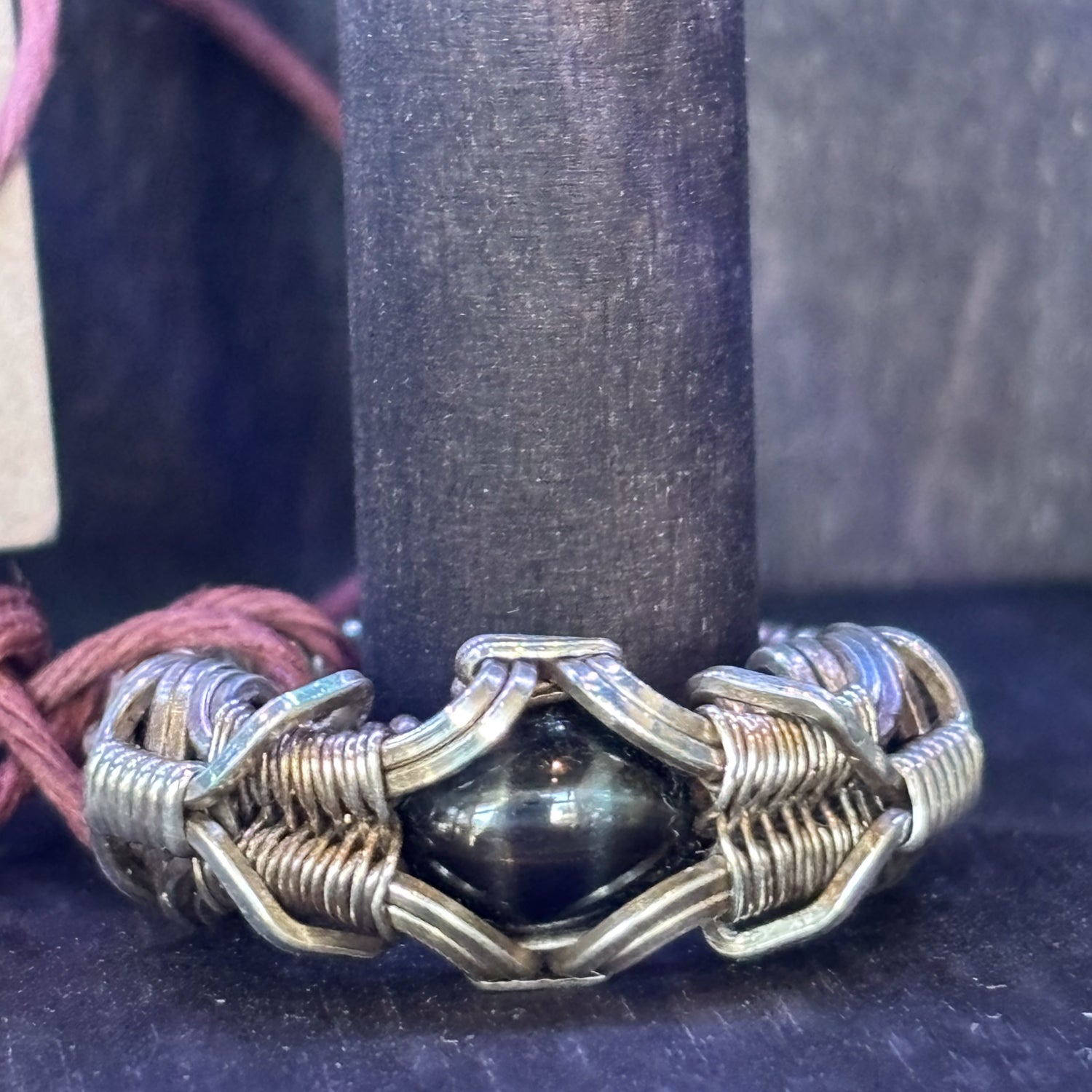 Silver bracelet with a central black bead on a dark background