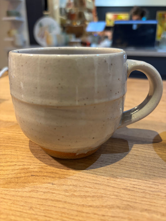 Beige ceramic mug on a wooden surface with a blurred indoor background